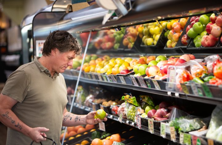 Aric Putnam looking over fresh produce on the shelves of a local food co-op.