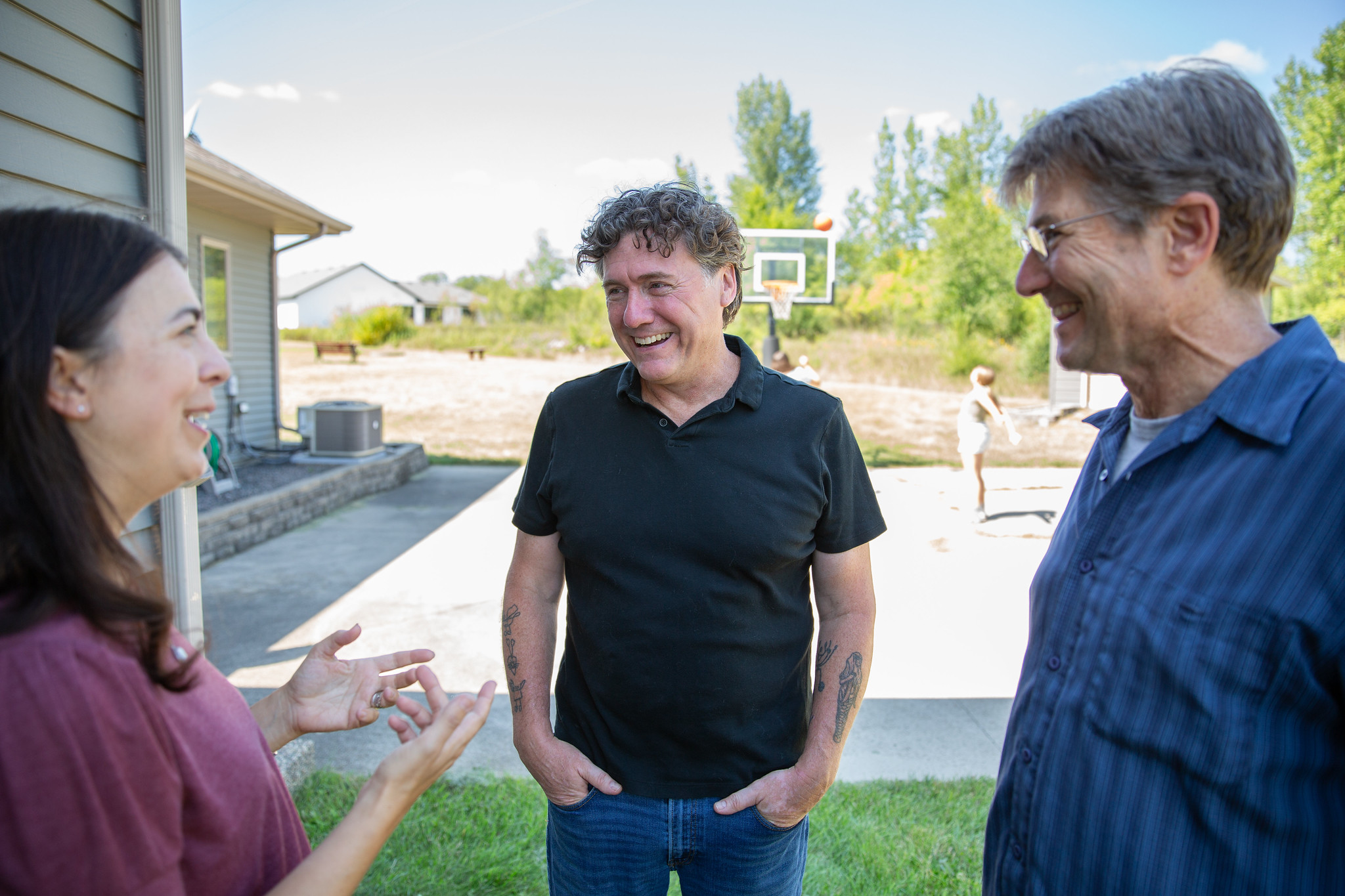 Aric Putnam standing outside a house in conversation with two neighbors.