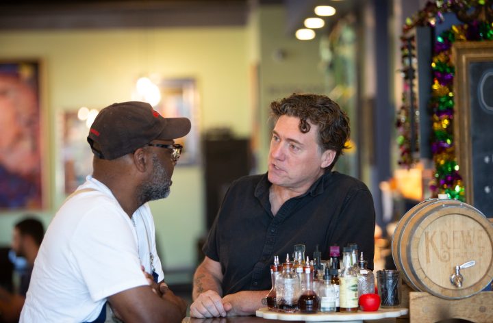 Aric Putnam leaning on the bar of a local restaurant in conversation with its owner.